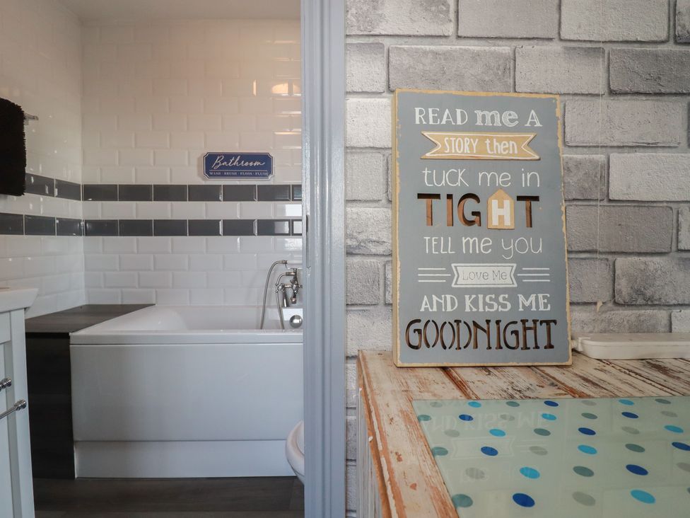 A bathroom with a bathtub and a decorative sign at Penthouse No.3 in Newquay