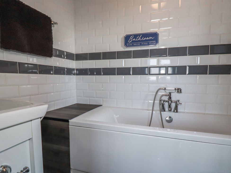 A bathroom featuring a bathtub and a wall sign at Penthouse No.3 in Newquay