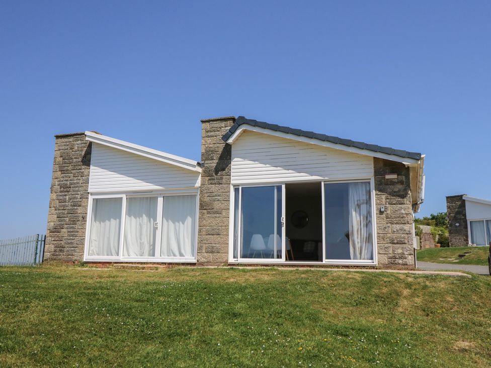 A house with sliding glass doors and a stone facade at 57 Cliff End Freshwater