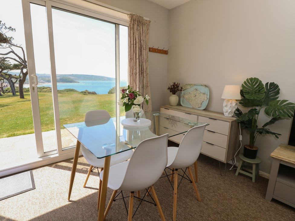 A dining room with a glass table and chairs at 57 Cliff End in Freshwater