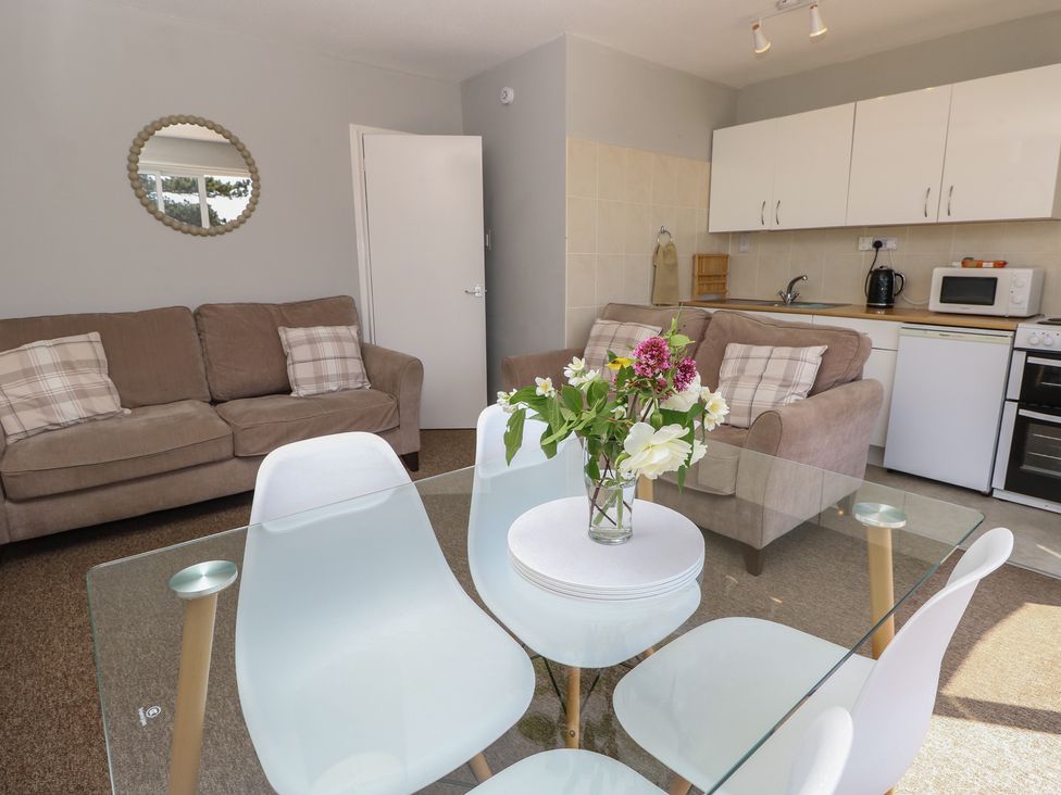 A living room with a dining table and kitchen area at 57 Cliff End in Freshwater