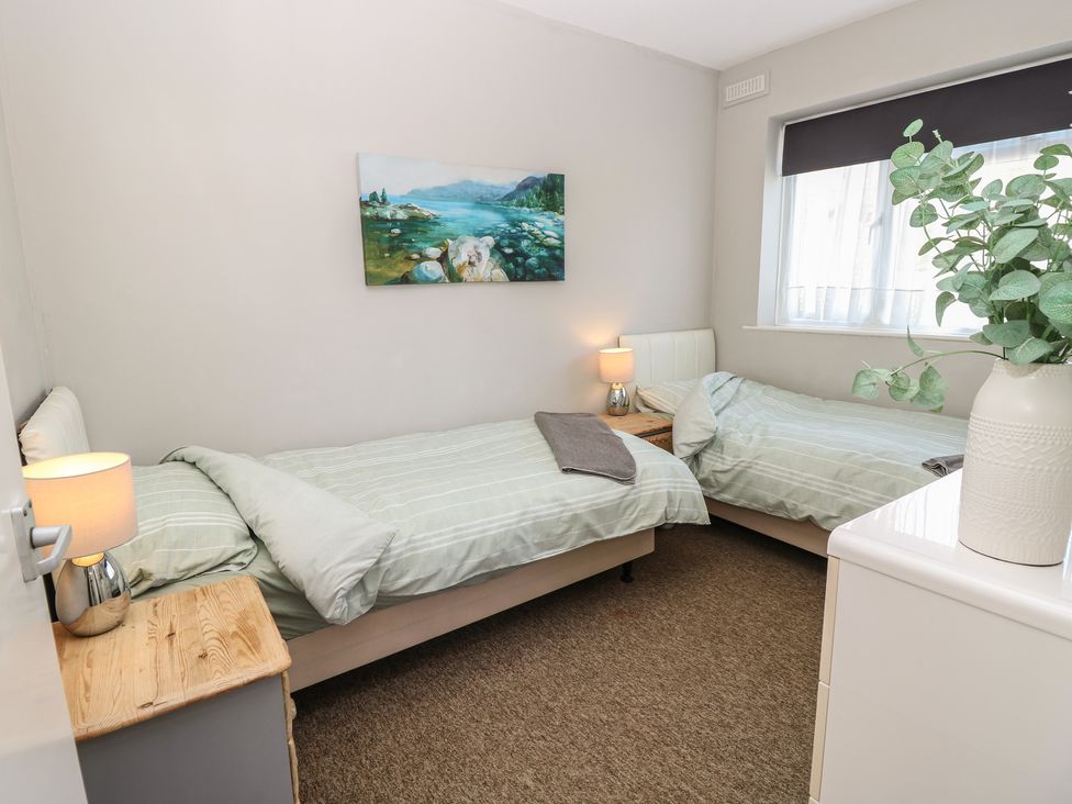 A bedroom with two beds and a nightstand at 57 Cliff End Freshwater