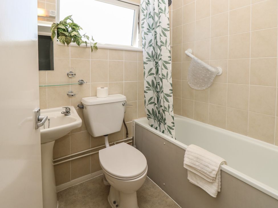 A bathroom with a bathtub, toilet, and sink at 57 Cliff End Freshwater