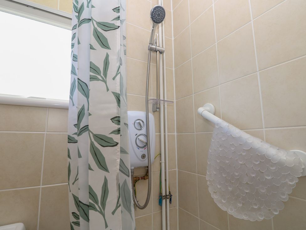A bathroom with a shower and water heater at 57 Cliff End Freshwater