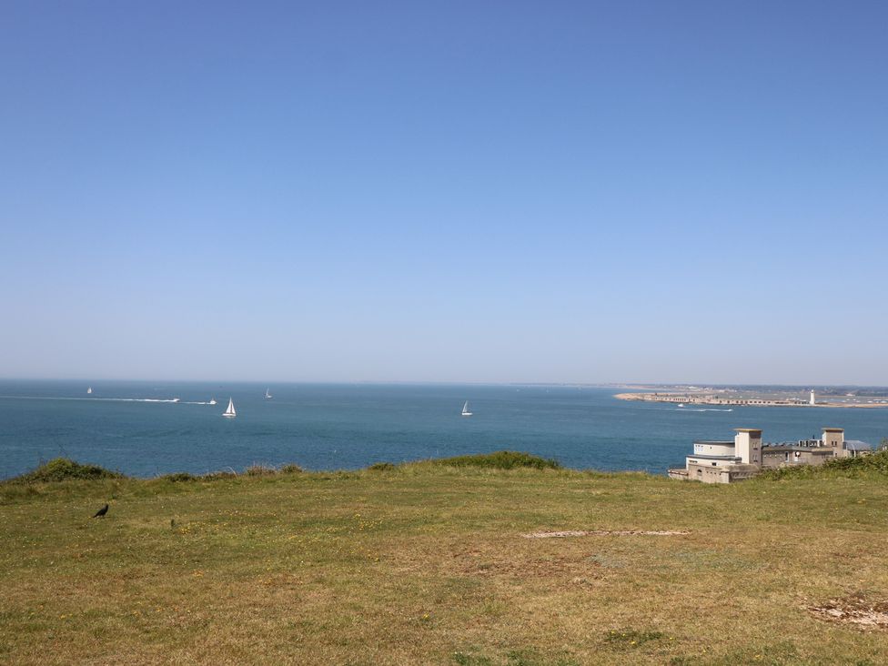 A view of the ocean with sailboats and grass at 57 Cliff End in Freshwater