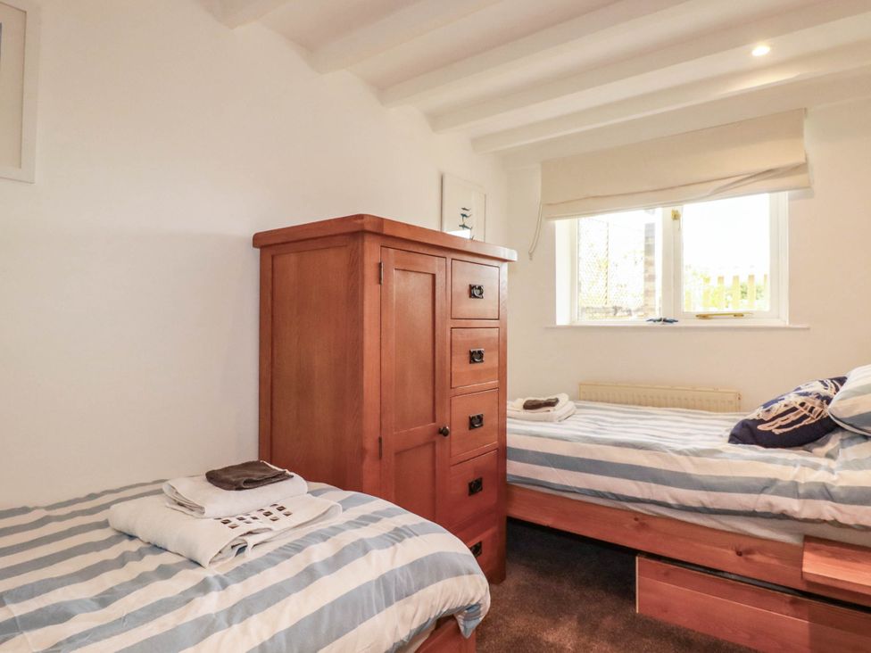 A bedroom with two beds and a wardrobe at Little House in Wadebridge