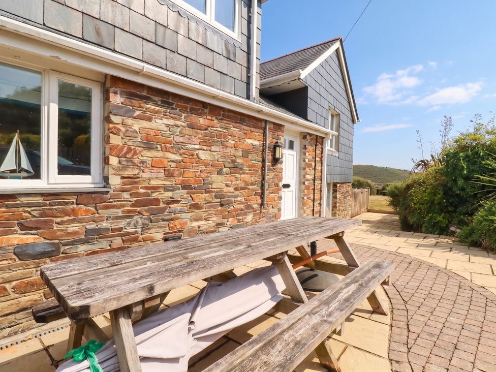 An outdoor area with a wooden table and stone wall at Little House in Wadebridge