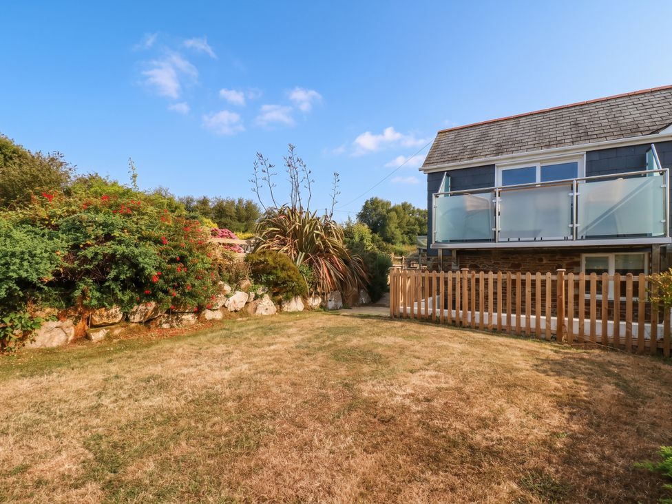 A garden with a fence and house with a balcony at Little House in Wadebridge