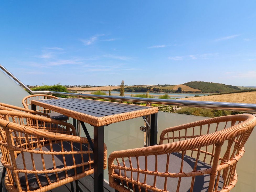 A balcony with table and chairs overlooking a landscape at Little House in Wadebridge