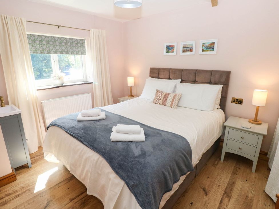 A bedroom with a bed and nightstand at The Old Dairy near Solva