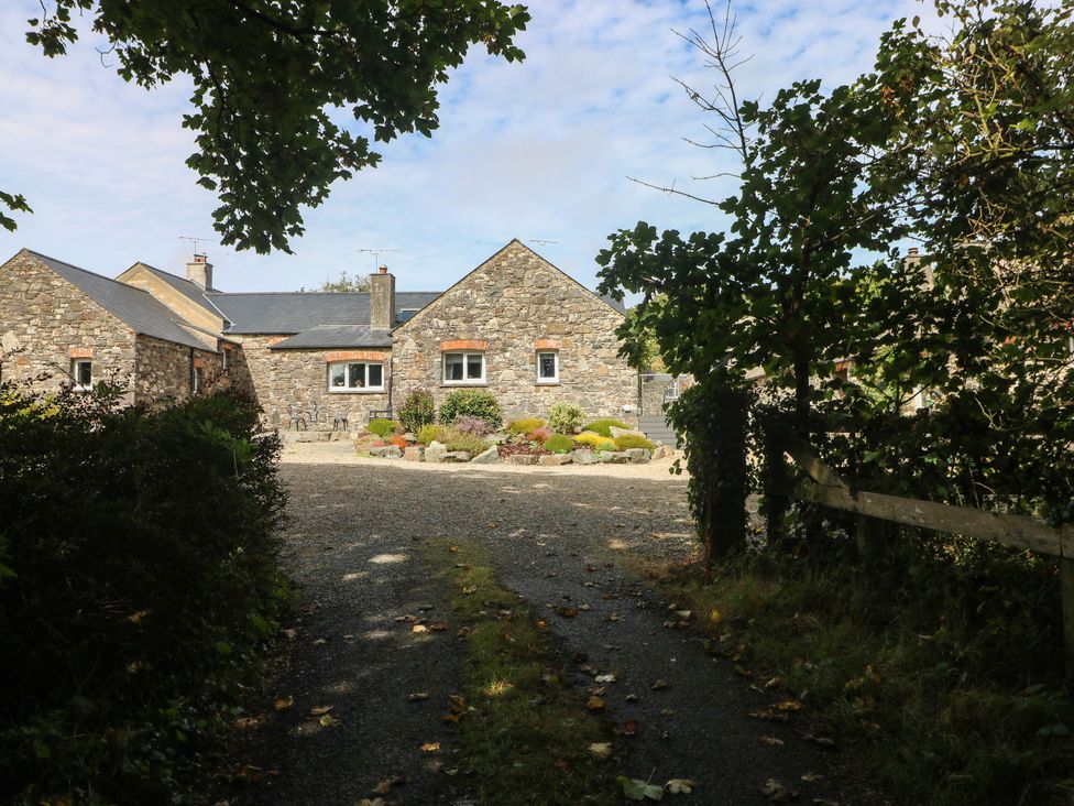 A stone house with a gravel driveway and gardens at The Old Dairy near Solva
