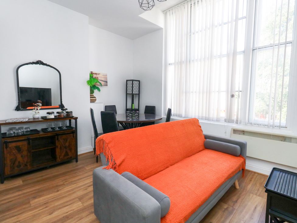 A living room with a sofa and a dining table at Ocean Breeze in Weymouth