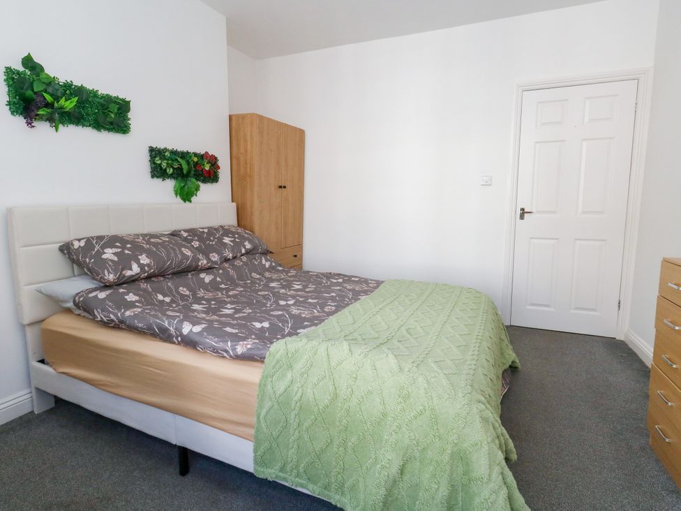 A bedroom with a bed and wooden wardrobe at Ocean Breeze in Weymouth