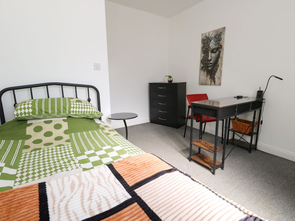 A bedroom with a bed, desk, and chair at Ocean Breeze in Weymouth