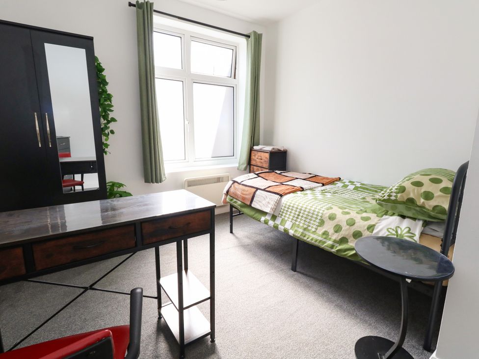 A bedroom with a bed, desk, and wardrobe at Ocean Breeze in Weymouth