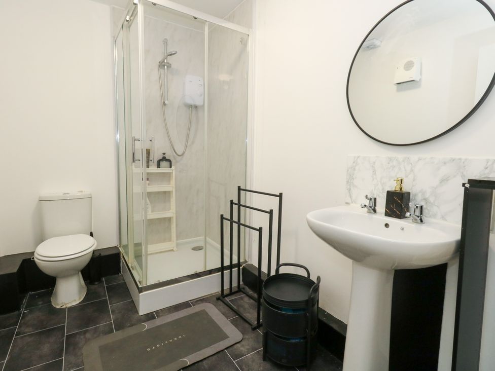 A bathroom with a shower, toilet, sink, and mirror at Ocean Breeze in Weymouth