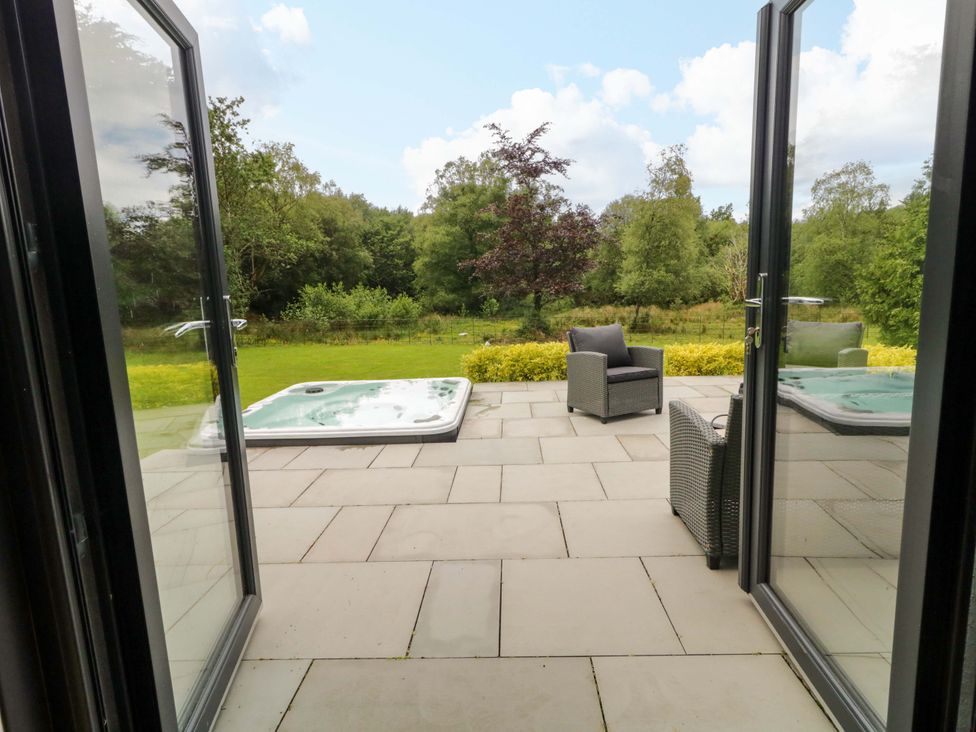 A patio with a hot tub and chair overlooking a garden at 3 bed property 