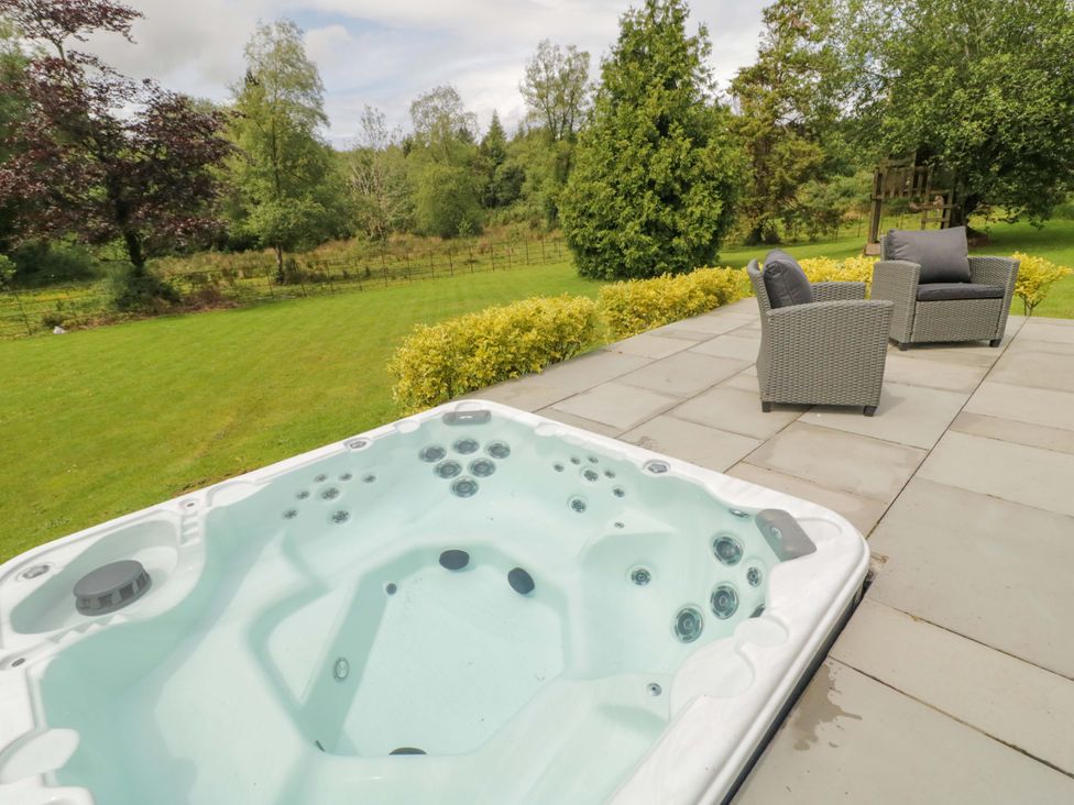 An outdoor area with a hot tub and chairs in a garden