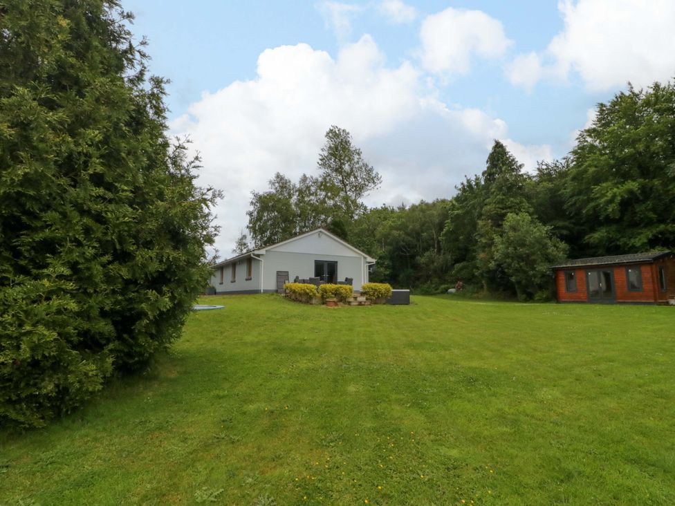 A house with green garden and trees in the background at 3 bed property