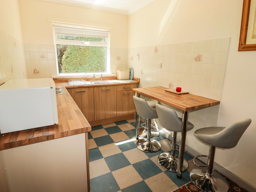 A kitchen with counters and bar stools at Cottage 1 in Tenby