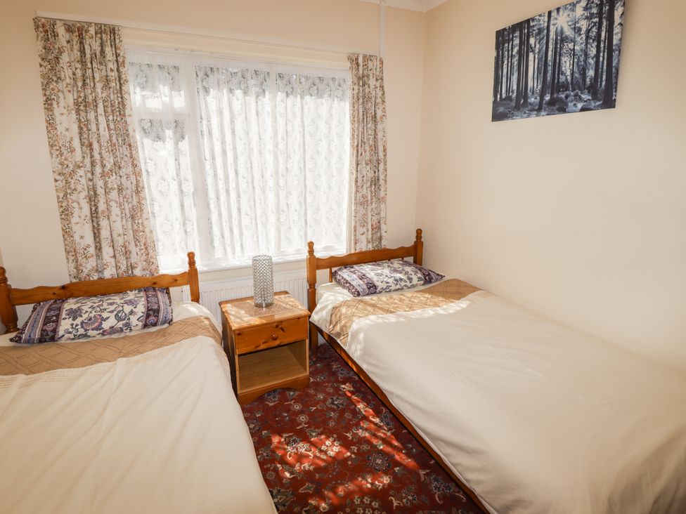 A bedroom with two beds and a bedside table at Cottage 1 in Tenby