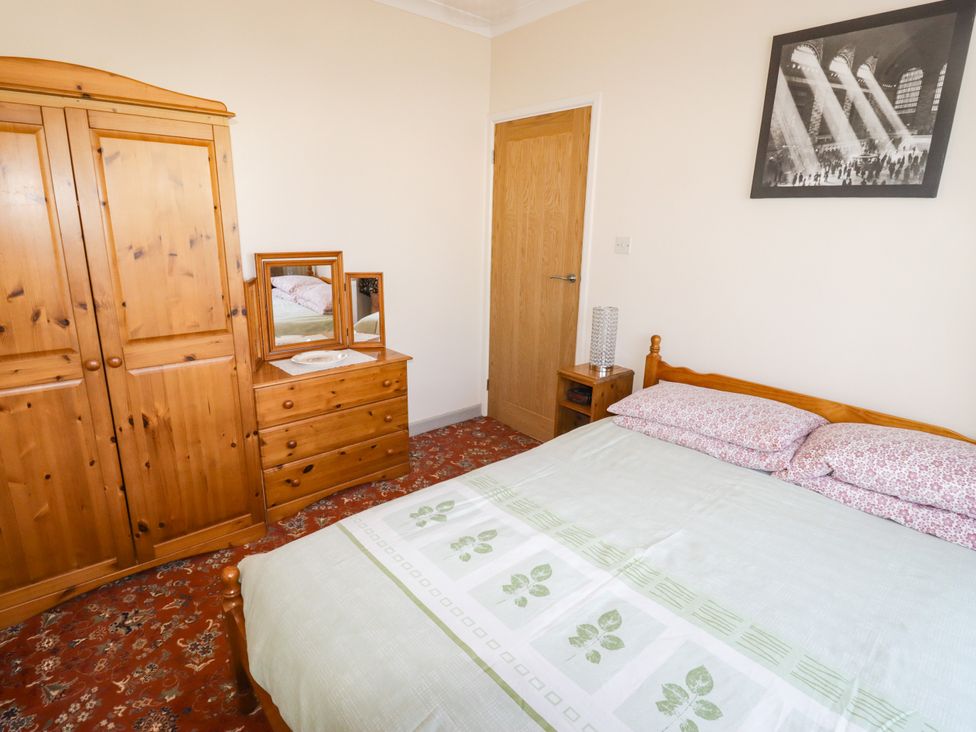 A bedroom with a bed and wooden furniture at Cottage 1 in Tenby