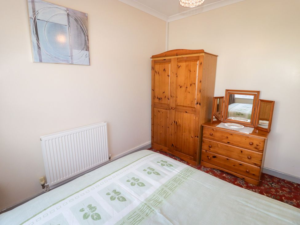 A bedroom with a bed and wooden furniture at Cottage 1 in Tenby