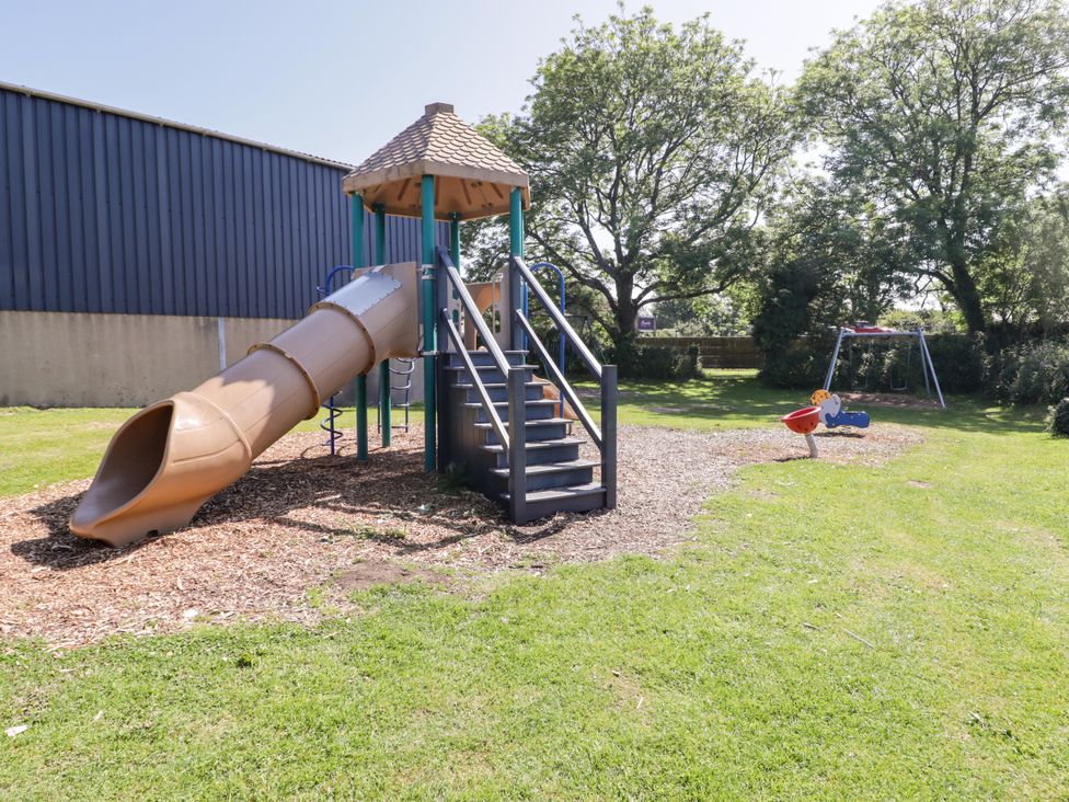 A playground with a slide and swings at Cottage 1 in Tenby