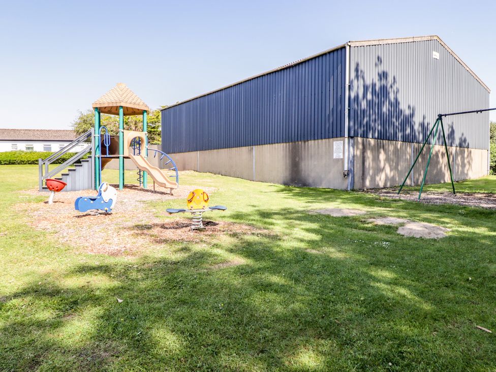 A playground with a slide and swings at Cottage 1 in Tenby