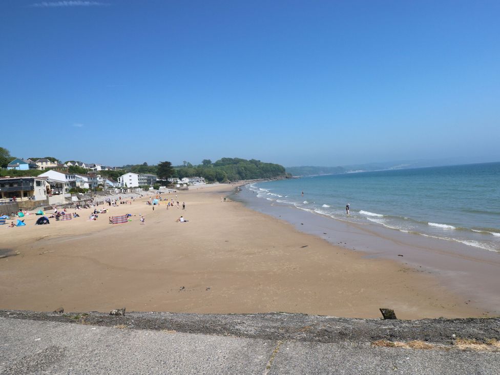 A beach with people and residential buildings at Cottage 1 in Tenby