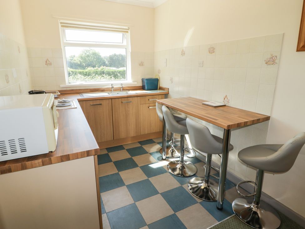 A kitchen with a sink and bar table at Cottage 3 in Tenby