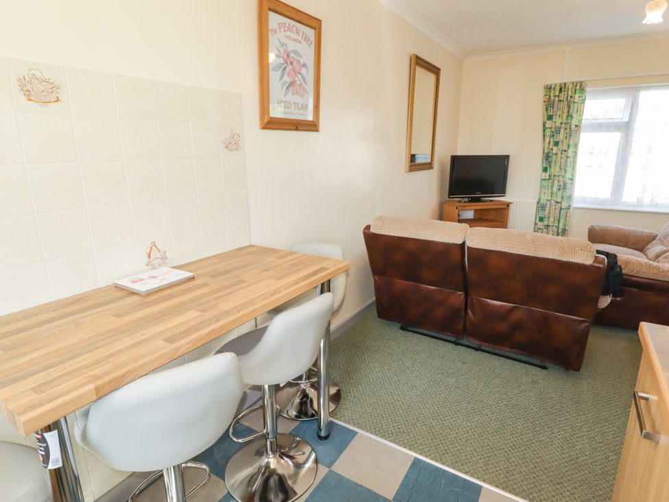 A living room with a bar table and stools and a television at Cottage 3 in Tenby