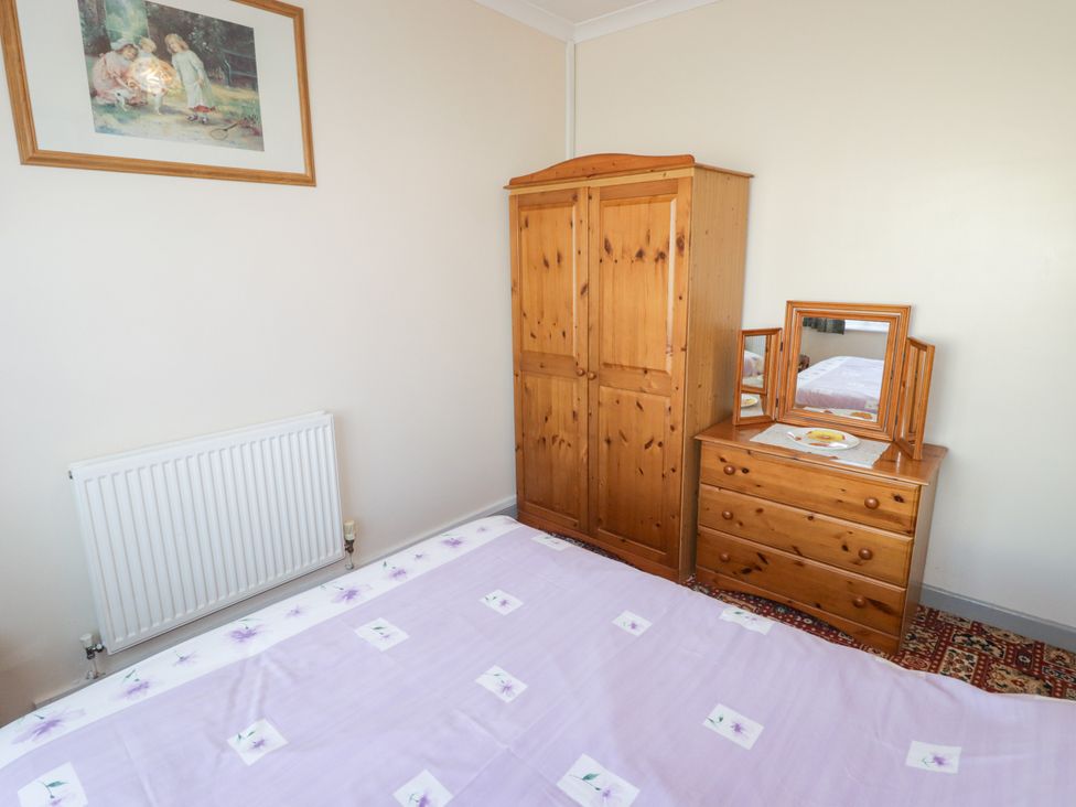 A bedroom with a wardrobe and dresser at Cottage 3 Tenby