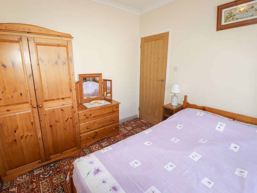 A bedroom with a bed and wardrobe at Cottage 3 in Tenby
