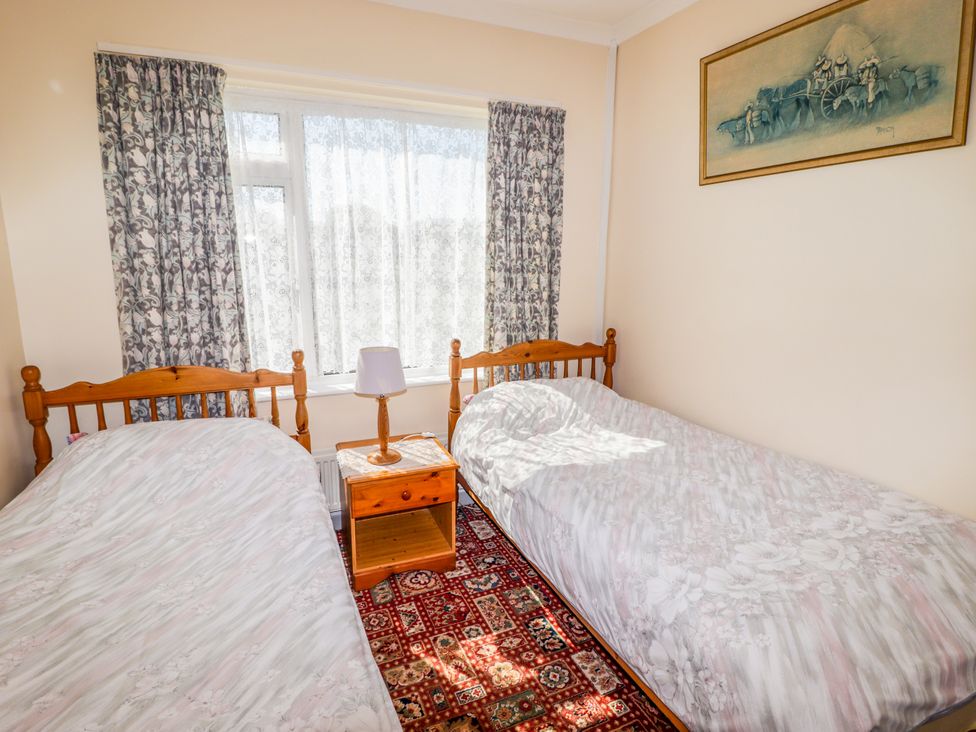 A bedroom with two beds and a side table with a lamp at Cottage 3 in Tenby