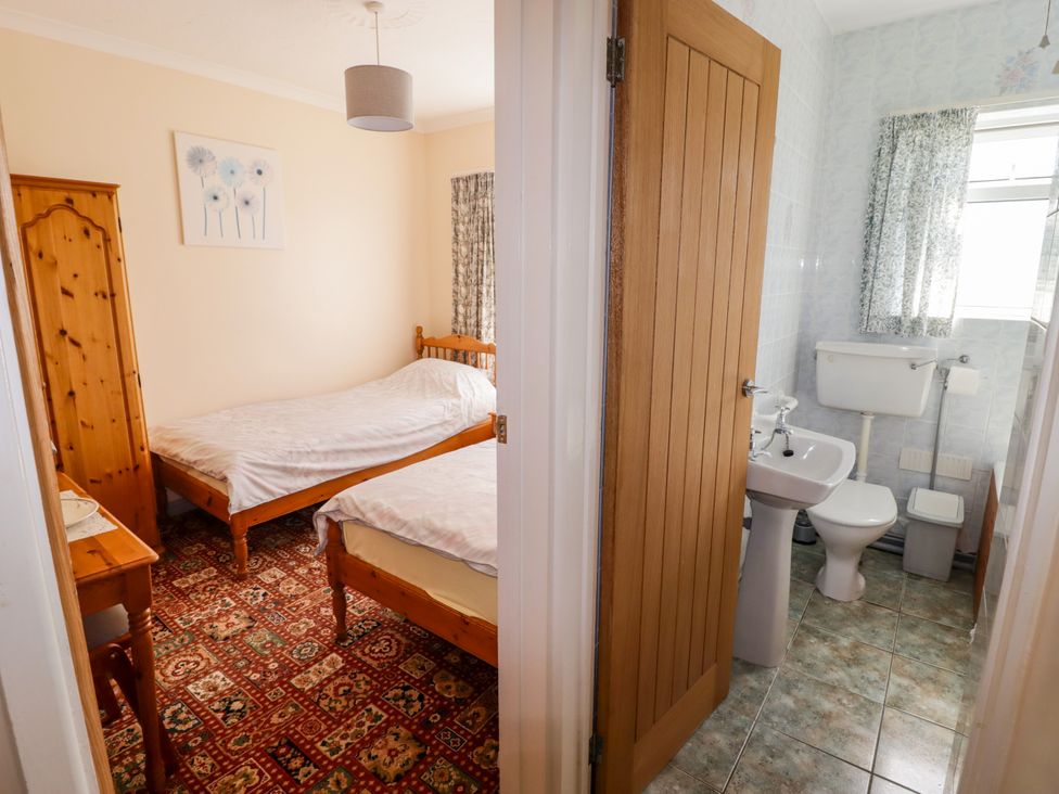 A bedroom with two beds and a bathroom with a toilet and sink at Cottage 3 in Tenby