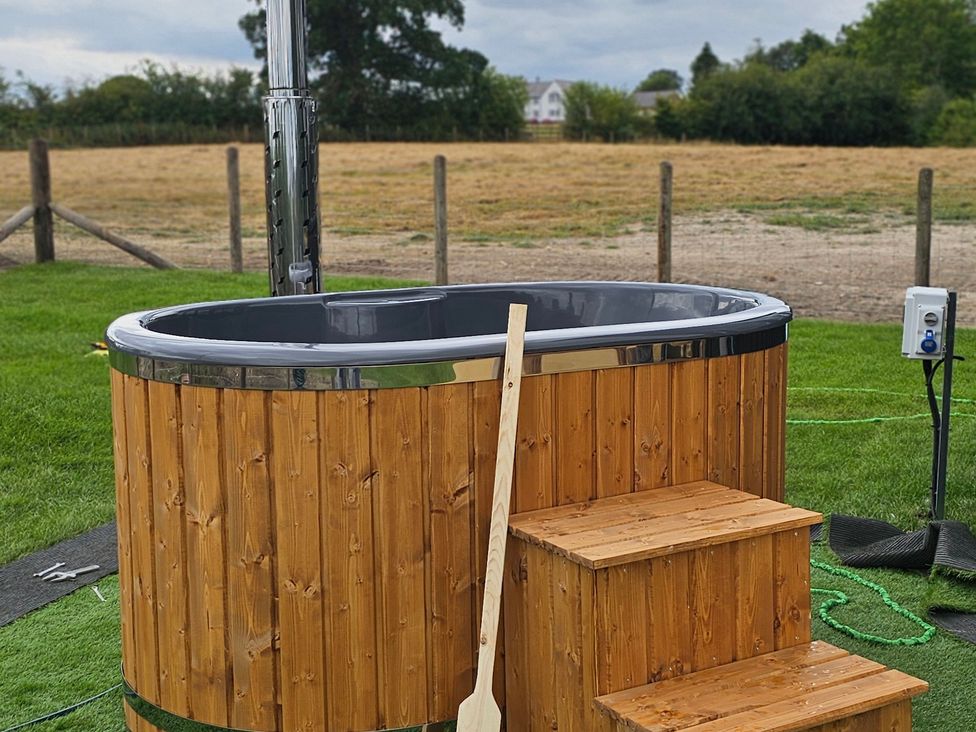 A hot tub with wooden steps and chimney in a garden at Balwen in Nercwys near Mold
