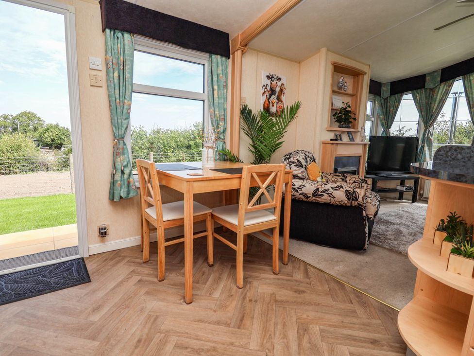A dining area with a table and chairs next to a living area at Balwen in Nercwys near Mold