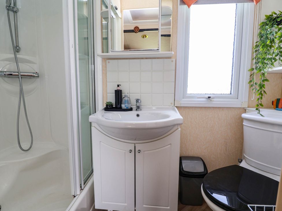A bathroom with a shower, sink, toilet, and window at Balwen in Nercwys near Mold