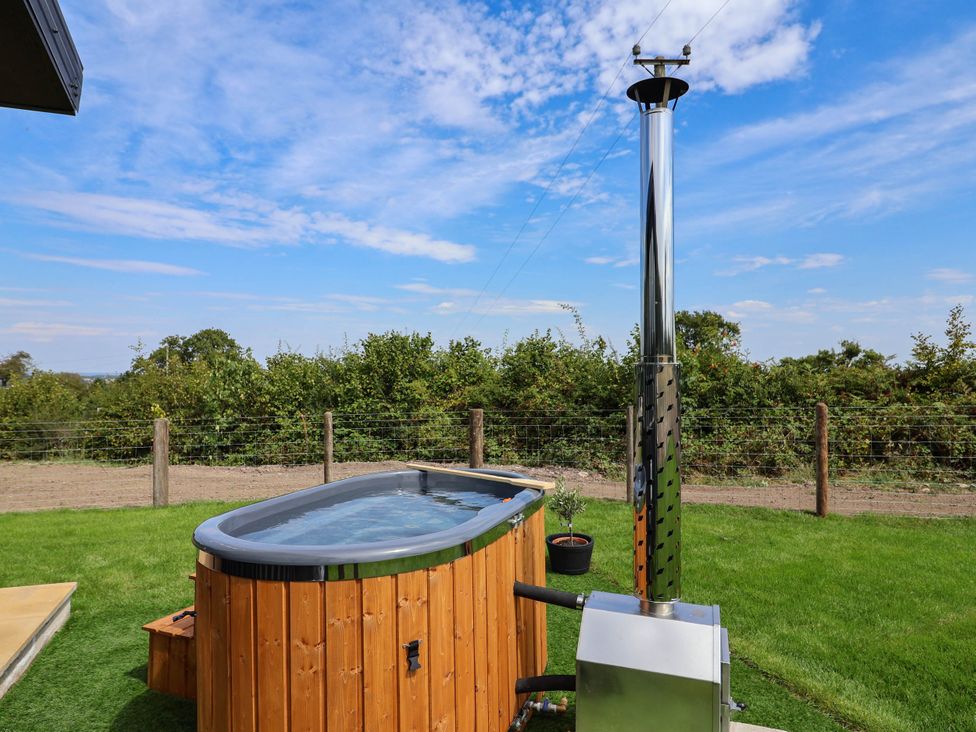 A hot tub with a chimney and grass area at Balwen Nercwys near Mold