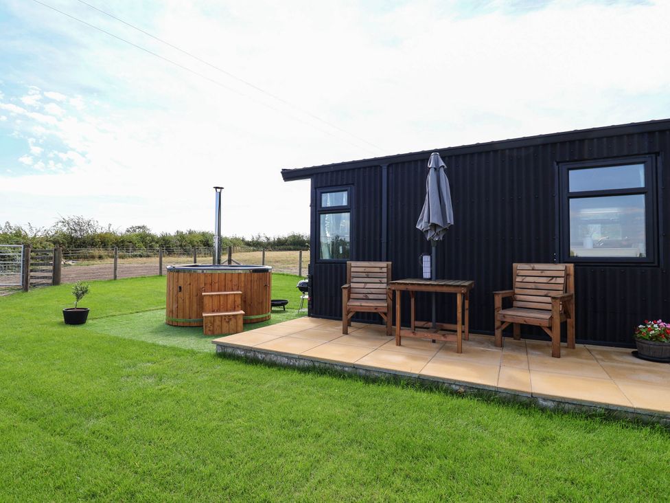 An outdoor area with a hot tub and seating at Balwen in Nercwys near Mold
