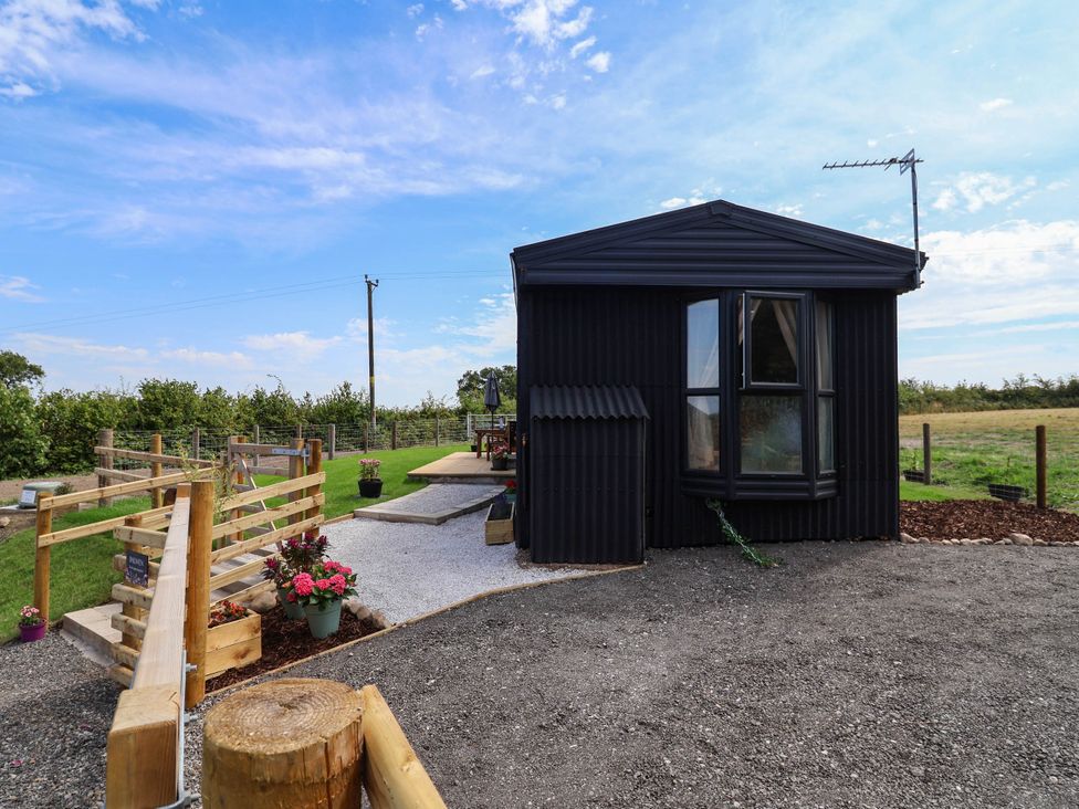 An outdoor area with a black building and garden space at Balwen in Nercwys near Mold