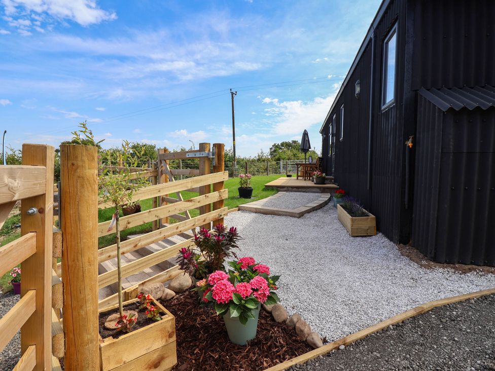 An outdoor area with gravel pathway, flowers, wooden fence and a table at Balwen in Nercwys near Mold