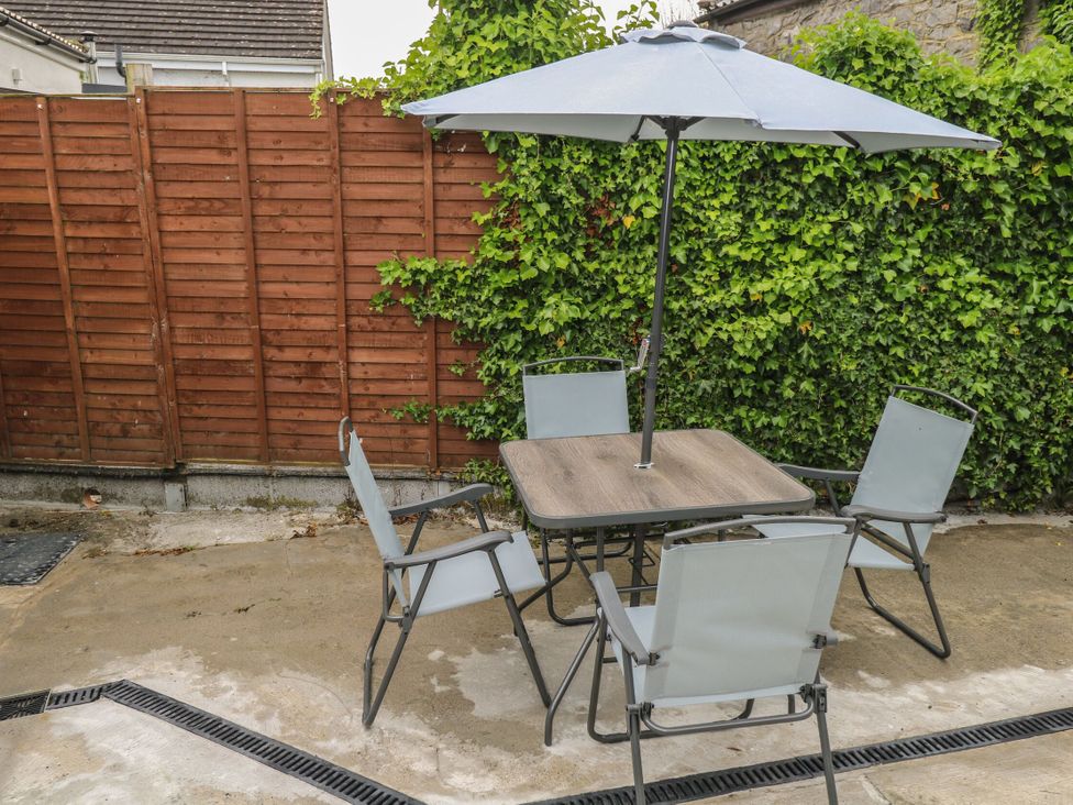 A garden with a table and chairs under an umbrella at Ti Maolla in Hollymount