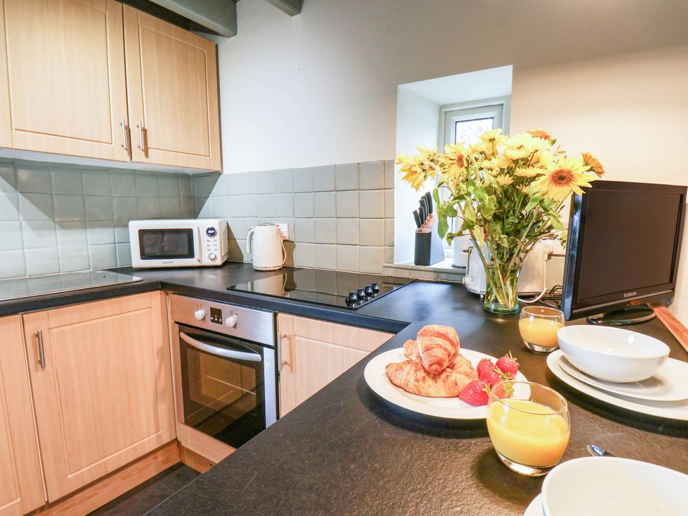 A kitchen with microwave and flowers on the counter at The Snug Glaisdale