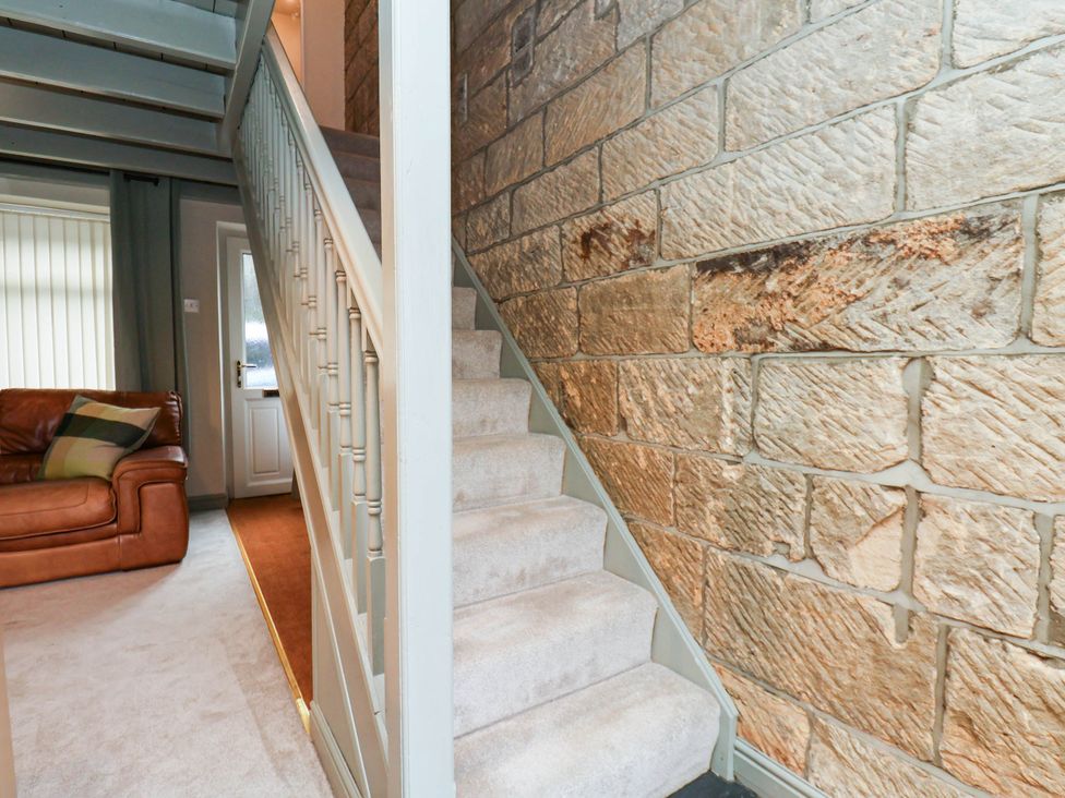 A hallway with a staircase and sofa at The Snug Glaisdale