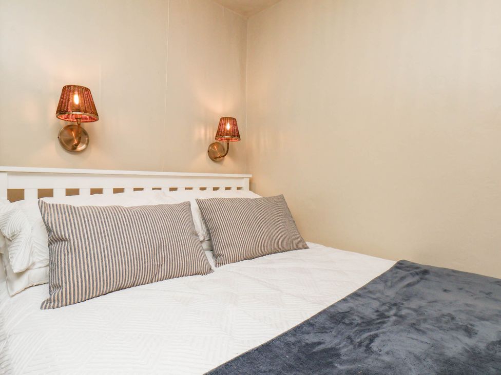 A bedroom with a bed and wall lamps at The Snug Glaisdale