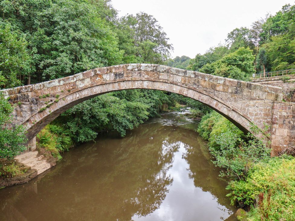 A stone bridge over a river surrounded by trees at The Snug Glaisdale in Glaisdale