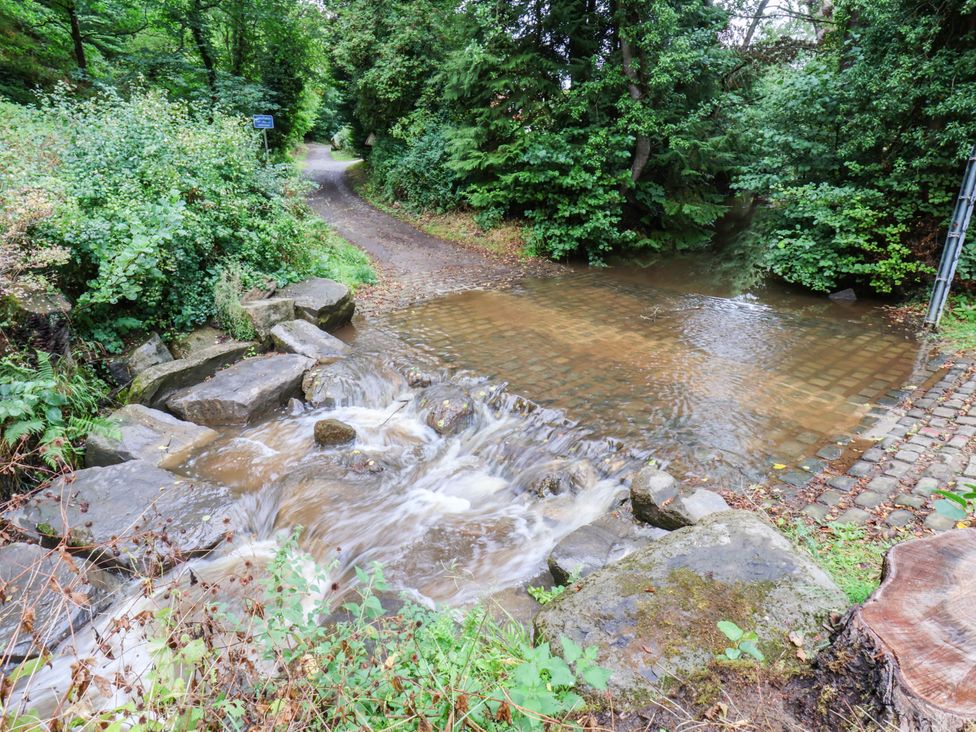 A stream flowing over cobblestones beside a path in Glaisdale