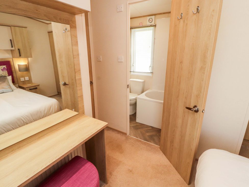 A bedroom with a dressing table and an attached bathroom at Caravan